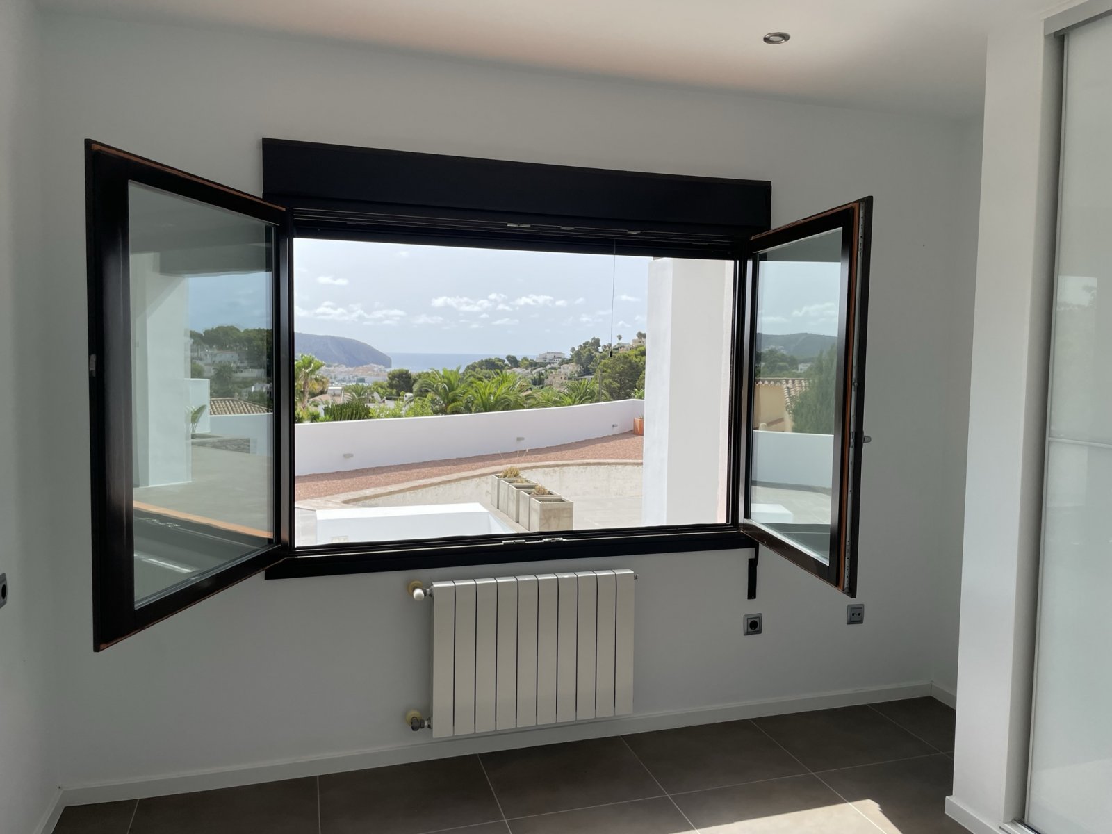 Panorama-Ausblick: Moderne Fensterfront mit atemberaubender Berglandschaft und Meerblick Panorama-Ausblick: Moderne Fensterfront mit atemberaubender Berglandschaft und Meerblick