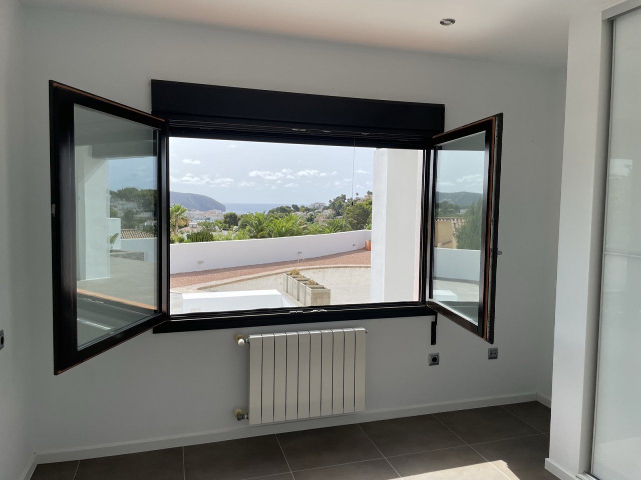 Panorama-Ausblick: Moderne Fensterfront mit atemberaubender Berglandschaft und Meerblick Panorama-Ausblick: Moderne Fensterfront mit atemberaubender Berglandschaft und Meerblick
