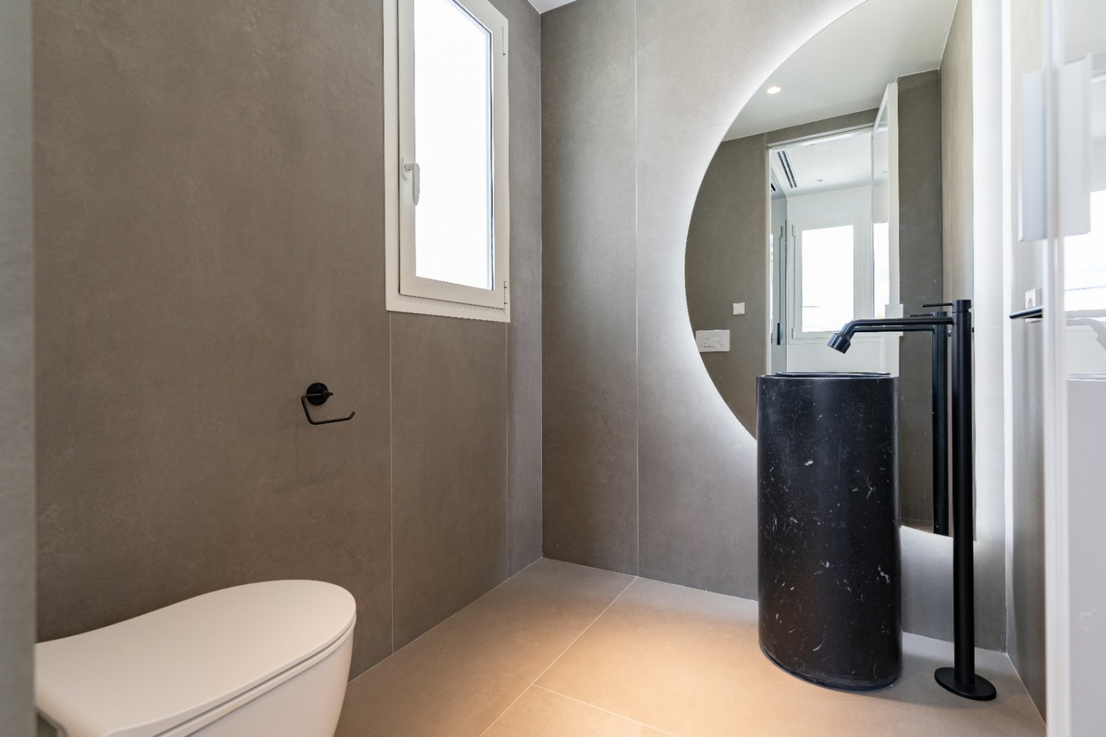 Design-Highlight: Moderne Gästetoilette mit skulpturalem Waschbecken und elegantem Rundspiegel Design-Highlight: Moderne Gästetoilette mit skulpturalem Waschbecken und elegantem Rundspiegel