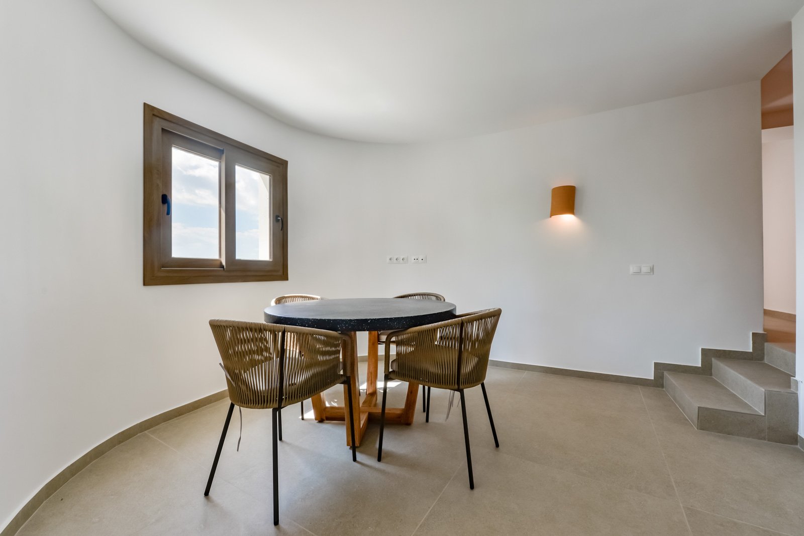 Lichtdurchfluteter Essbereich mit elegantem Naturstein-Esstisch und geschwungener Architektur Lichtdurchfluteter Essbereich mit elegantem Naturstein-Esstisch und geschwungener Architektur