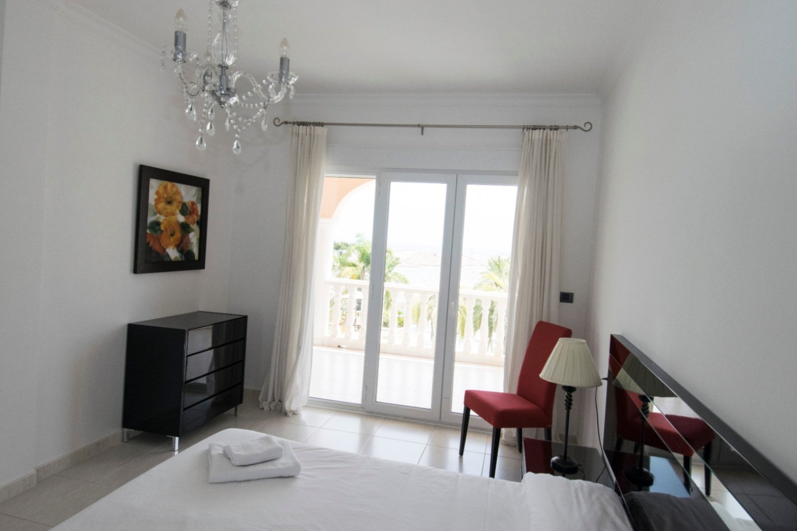 Bright bedroom with balcony access and an elegant crystal chandelier - your retreat with a view! Bright bedroom with balcony access and an elegant crystal chandelier - your retreat with a view!