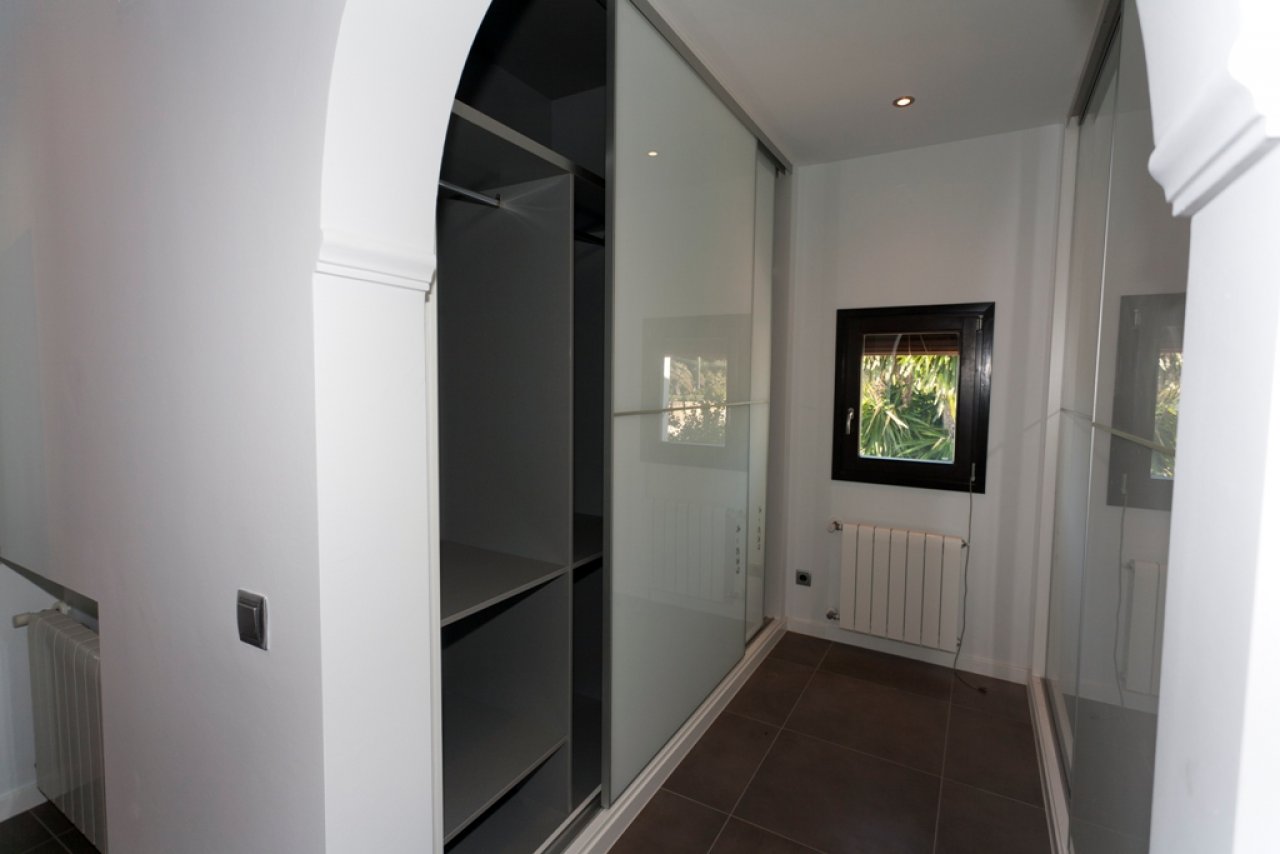 Brightly lit walk-in wardrobe with intelligent layout and elegant sliding door system Brightly lit walk-in wardrobe with intelligent layout and elegant sliding door system